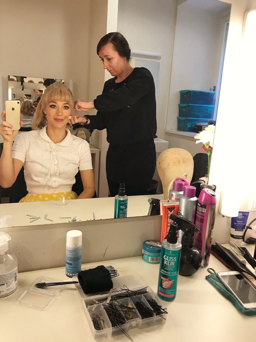 Auf diesem Bild bekomme ich von unserer Hair- und Make-Up Artistin Susan die Perücke auf den Kopf gesetzt und fixiert.