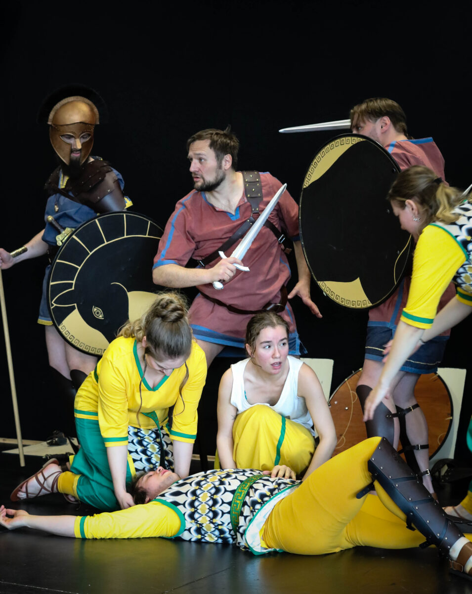 Hintere Reihe von links nach rechts: Manuel Schwirtz (Odysseus), Martin Schupfinger (Dardanos), Christoph Mack (Kosmas), Vorne von links nach rechts: Eva Müller (Trojanerin), Jazz Schröder-Cossio (Trojanerin) Katja Schadler (Trojanerin) Vorne liegend: Steven Rindler (Trojaner/Paris) &copy; Eva Krause